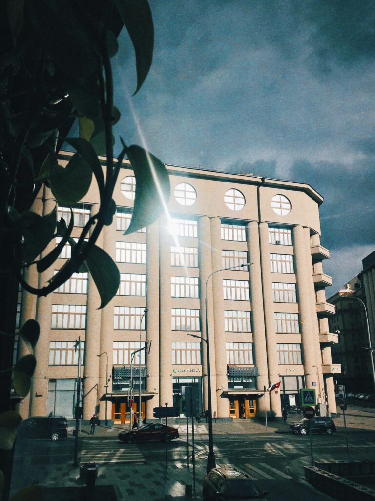 A street view of a modern commercial building facade under dramatic cloudy skies.